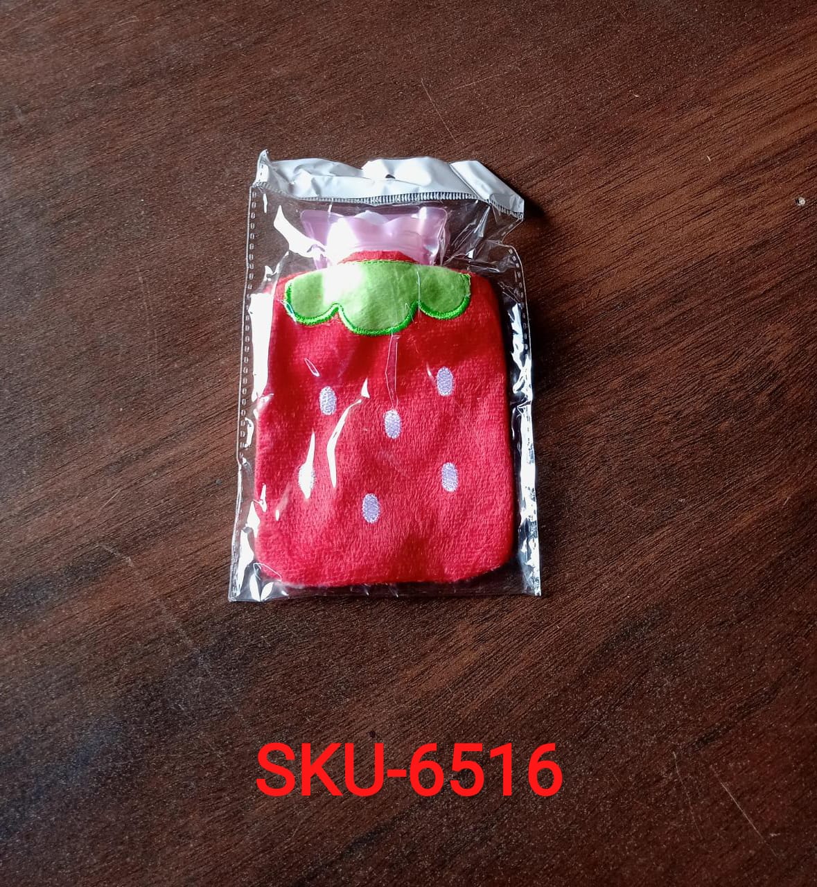 Strawberry print hot water bottle, highlighting its secure cap and durable material.