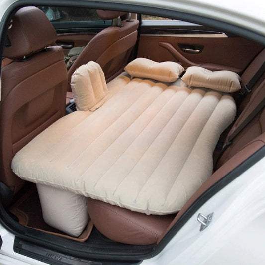 Inflatable car bed with two pillows and pump set up in a car's back seat.