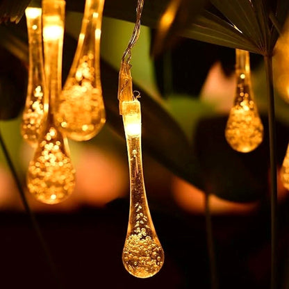 Crystal water drop LED string lights glowing warmly in darkness.
