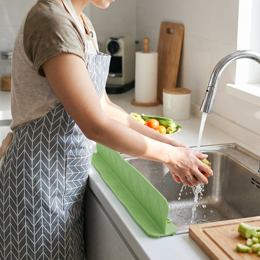Flexible silicone kitchen sink splash guard protecting countertop during vegetable washing.