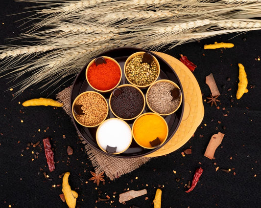 A round plastic masala spice box with seven compartments and a clear lid, showcasing vibrant spices.